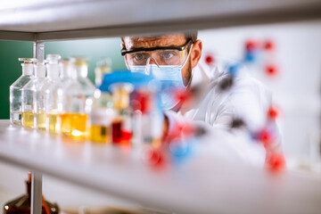 Young researcher with protective goggles checking test tubes