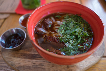 soup with meat and noodles in a clay plate with sauces
