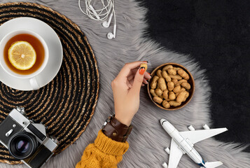 Womans hand in sweater with old instant camera plane and tea