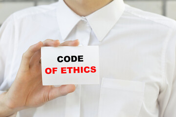 Businessman putting a card with text CODE OF ETHECS in the pocket