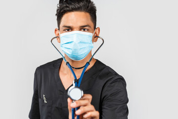 Indian / Asian doctor with stethoscope, in medical facial mask on gray background. protection against coronavirus