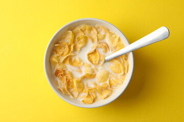 Bowl with muesli and milk on yellow background