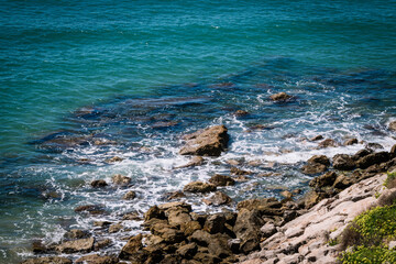Rocky cliff that ends in the sea with the waves breaking on the rocks.