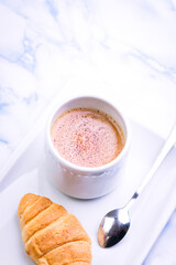 Close-up of breakfast consisting of croissants and latte with white dishes.
