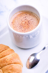 Close-up of breakfast consisting of croissants and latte with white dishes.