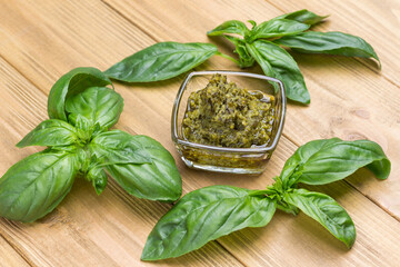Basil leaves and pesto sauce in glass cup.