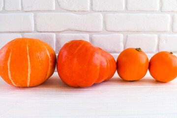 Orange pumpkins on a white wooden table against a white brick wall background. Harvest concept.