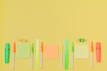 Flat lay border with school supplies on a yellow background