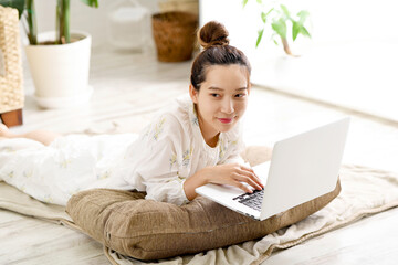 寝ながらパソコンを操作する若い女性