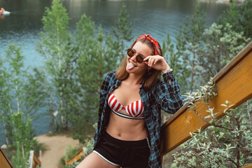 Young woman near wooden railing, smiling. Tourist concept. Camping. Nature rest. Forrest.