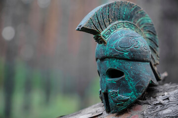 Historical Replica Spartan Warrior Helmet on pine forest background. Close up view of small...