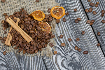 Coffee beans on coarse linen and spices. On a surface of brushed pine boards painted black and white.