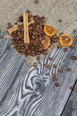 Coffee beans on coarse linen and spices. On a surface of brushed pine boards painted black and white.