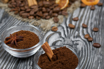 Coffee beans on coarse linen. Ground coffee in containers and spices. On a surface of brushed pine boards painted black and white.