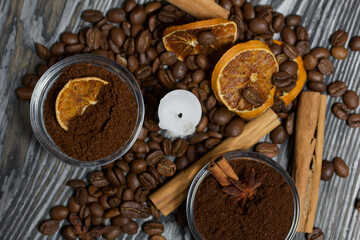 Coffee beans on rough linen and candle stub. Ground coffee in containers and spices. On a surface of brushed pine boards painted black and white.