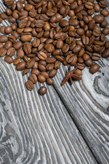 Coffee beans on a black-and-white brushed pine plank surface. Close-up shot.
