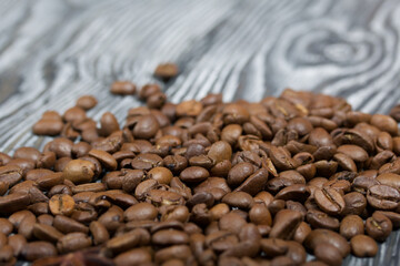 Coffee beans on a black-and-white brushed pine plank surface. Close-up shot.