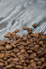 Coffee beans on a black-and-white brushed pine plank surface. Close-up shot.