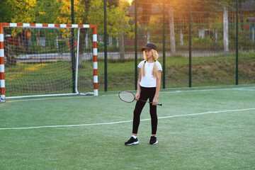 Girl with a racket in her hands on the sports field.