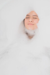 Beauty, spa, personal care. Young woman relaxes in the bath with foam