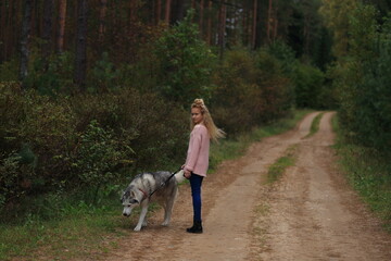 Obraz na płótnie Canvas A girl with a husky walks in the forest.