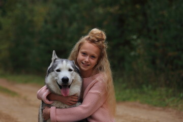 A girl with a husky walks in the forest.