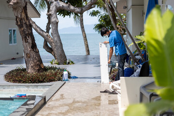 master men cleans the air conditioner in a tropical hotel.