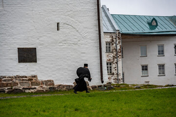 a monk in black clothes walks in the rain through the territory of the fortress-monastery on the Solovetsky Islands