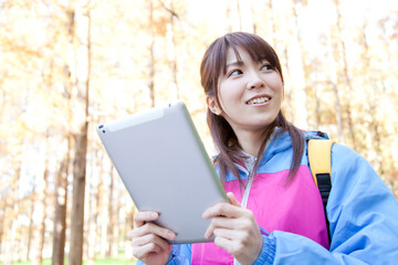 Fototapeta premium タブレットPCを見ながら山登りする女性