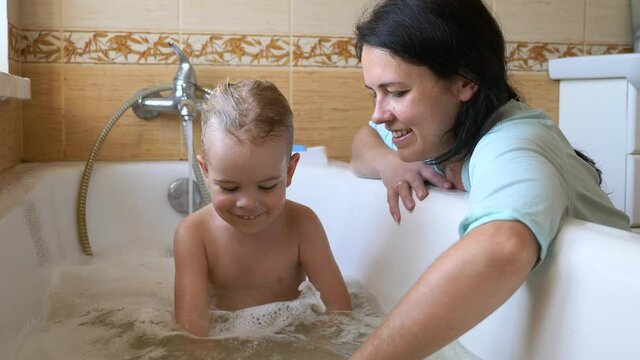 Mother Plays with Son in Bathroom. Parent Washing Child in Bathtub. 2x Slow motion 60 fps
