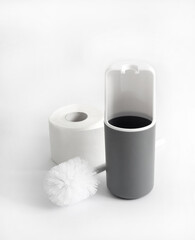 White and gray plastic toilet brush and roll of toilet paper on white background