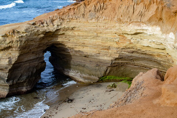 Fototapeta na wymiar Arch in the Cliffside with a Lonely Beach beside It at Sunset Cliffs in San Diego, California, USA