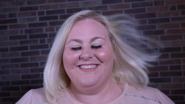 A funny shot of a blonde woman with long hair getting blown away. Shot in slow motion.  	