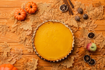 top view of pumpkin pie with autumnal decoration on wooden background