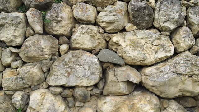 Texture of old stones of various forms with seams. Close up of shabby masonry. Stone wall from uneven different ancient friable cobblestones.