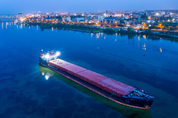 Large black dry cargo ship anchored on the Dnieper River awaiting loading with new cargo