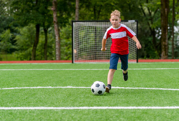 Obraz premium Football soccer training for kids. Boy running and kicking soccer ball. Young boy improving soccer skills