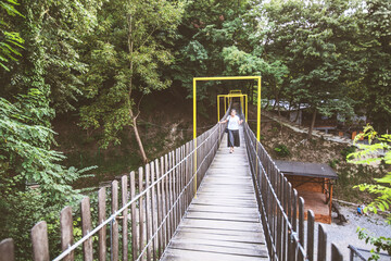 Woman crossing wooden suspension bridge
