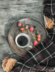 Autumn cozy composition. Cup of coffee, plaid, dried leaves on a wooden background. Autumn, fall concept. Flat lay, copy space