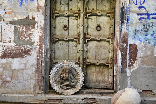 Old wooden door to aged ancient building. Rounded Hindu symbol with image of Ganesha god. Jodhpur, Rajasthan, India.