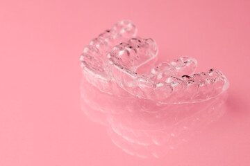 Two Invisible dental teeth aligners on the pink background. Orthodontic temporary removable braces for fixing teeth after alignment. Therapy after brackets. 