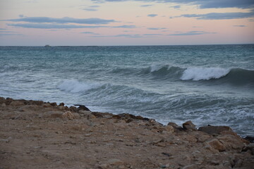 Fototapeta na wymiar Atardecer con olas del mar mediterráneo con horizonte