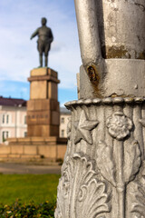 Authentic retro decoration on metal post with old statue in background, vertical