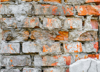The texture of an old, destroyed wall and a building made of red, orange uneven bricks with cracks,...