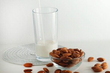 A glass with almond milk and the bowl with almonds
