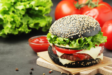 A black burger with vegetables and beef meat	