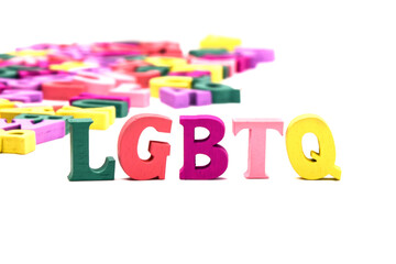 LGBTQ abbreviation: lesbian, gay, bisexual, transgendered, queer of multicolored wooden letters on a white background. Second plan with scattered colored letters.