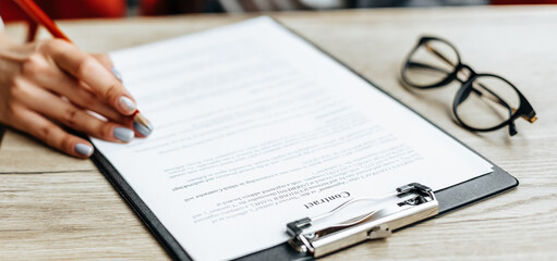 Fototapeta premium Young girl office worker or business lady signs documents. Concentrated businesswoman working with papers. Business concept