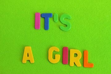 It Is A Girl, colorful letters, it is a girl is written on green background	