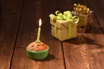 Mini birthday cake with candle and gifts on the background.